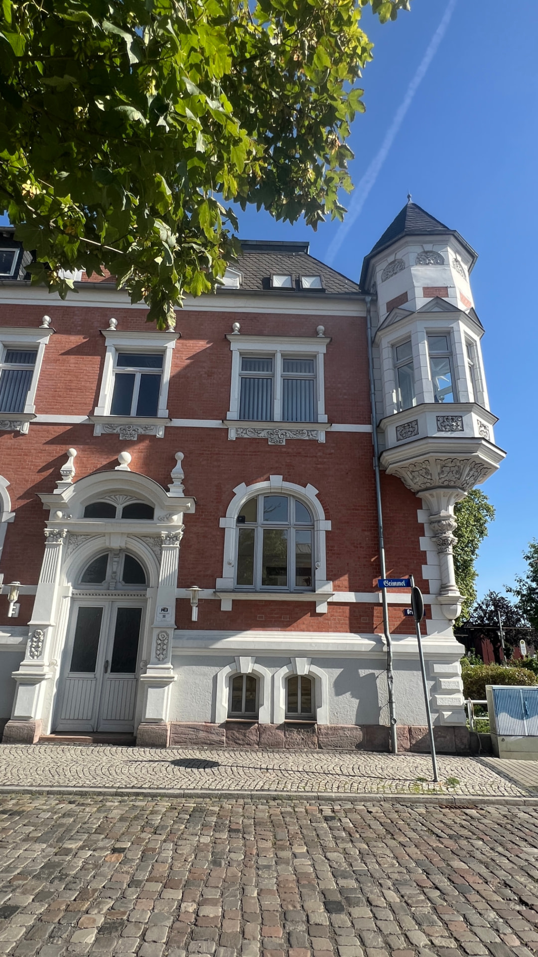 Klinkerfassade mit Erker unter Baumkrone – Straßenperspektive